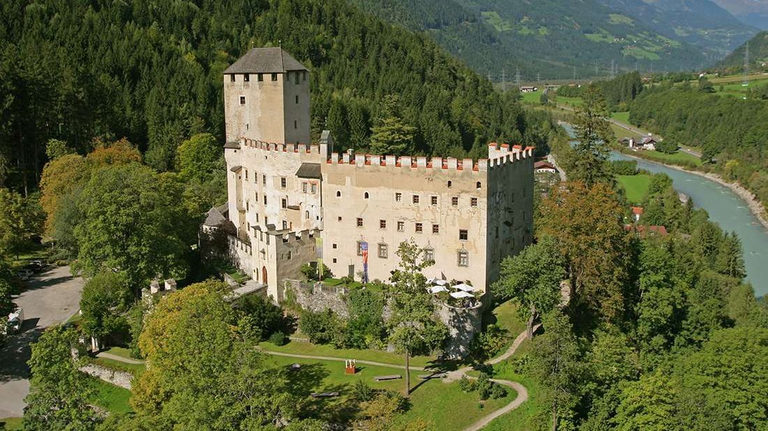 Schloss Bruck umgeben von grünen Wäldern und majestätischen Bergen in Tirol.