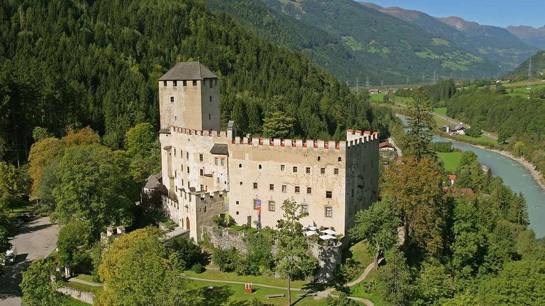 Schloss Bruck umgeben von grünen Wäldern und majestätischen Bergen in Tirol.